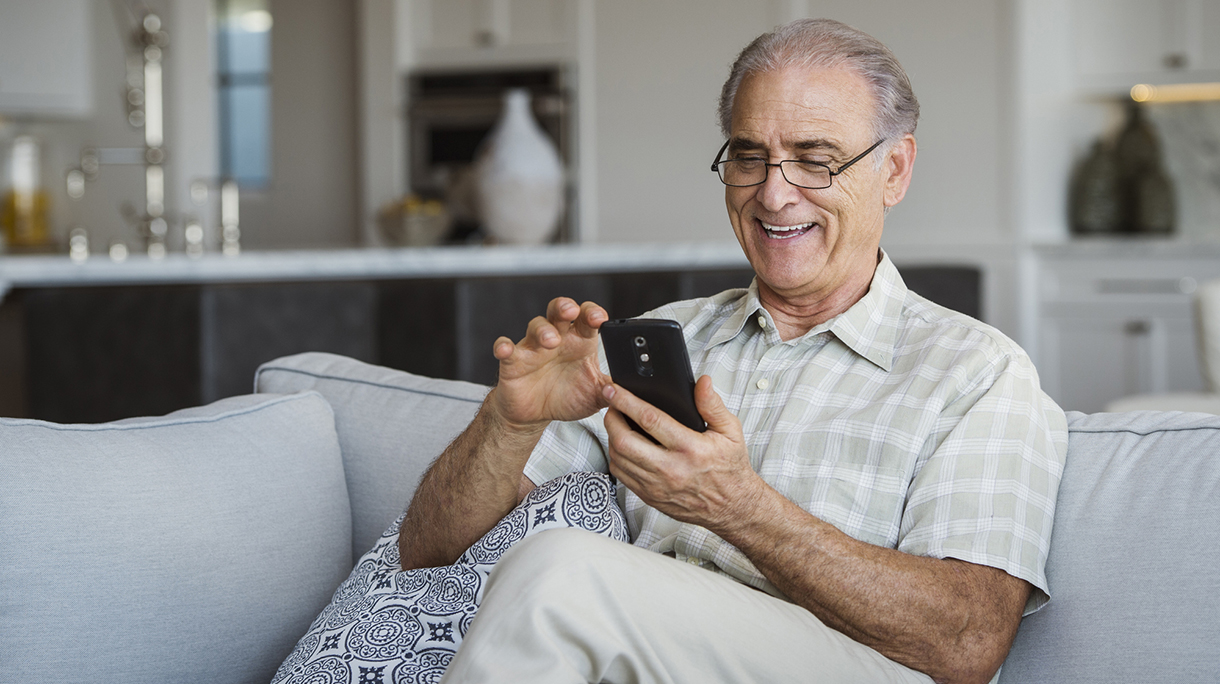 Caucasian man sitting on sofa texting on cell phone