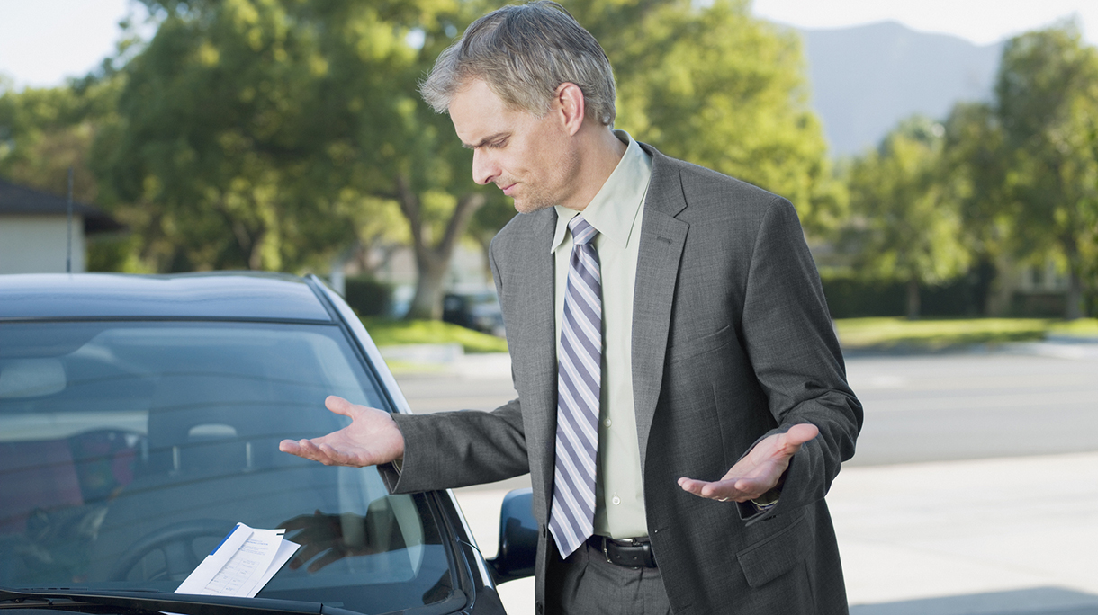 Frustrated businessman viewing parking ticket on windshield