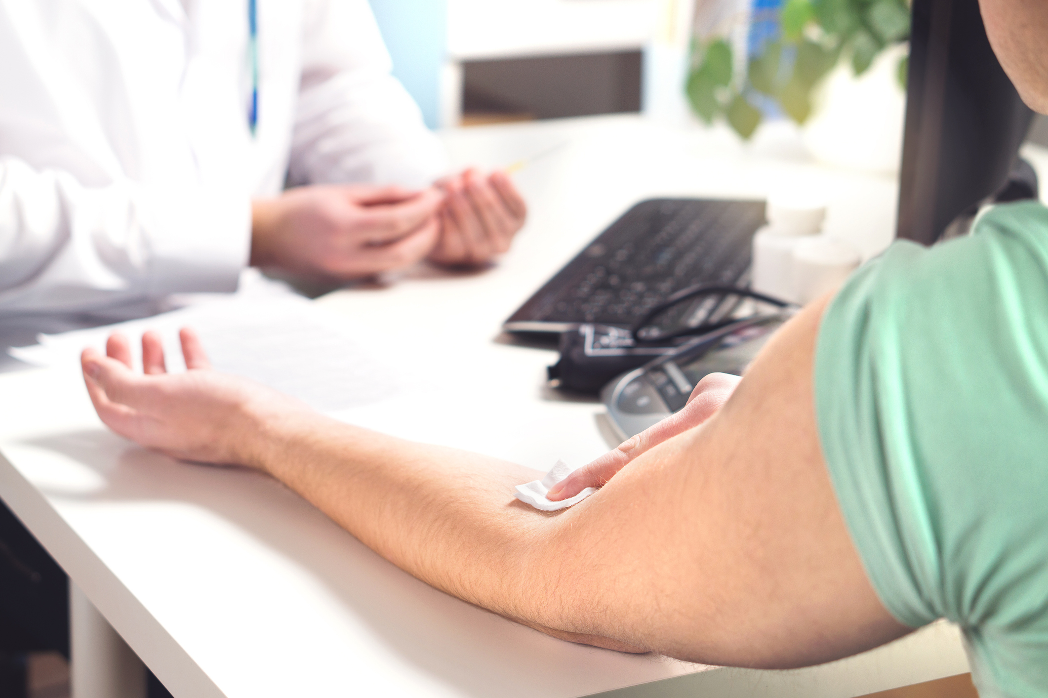 Blood test, sample or donation concept. Doctor with patient in hospital office, emergency room or laboratory. Person holding swab on arm after injection.