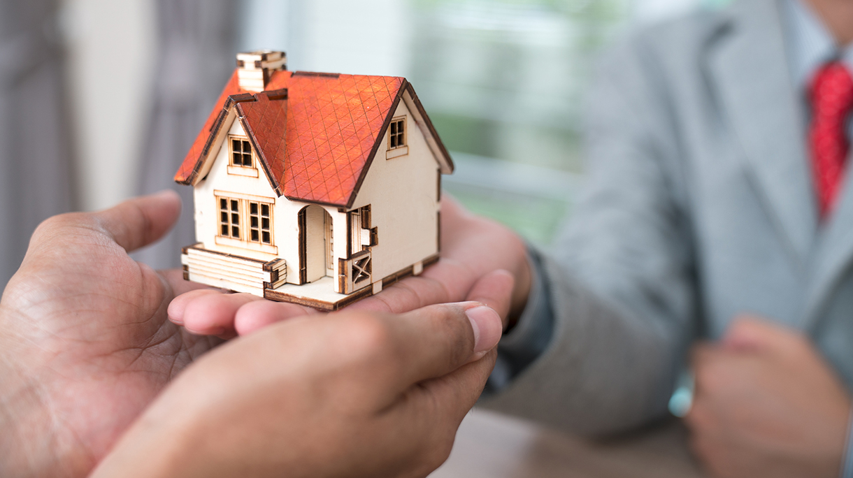 architecture, building, construction, real estate and property concept – close up of hands holding house or home model