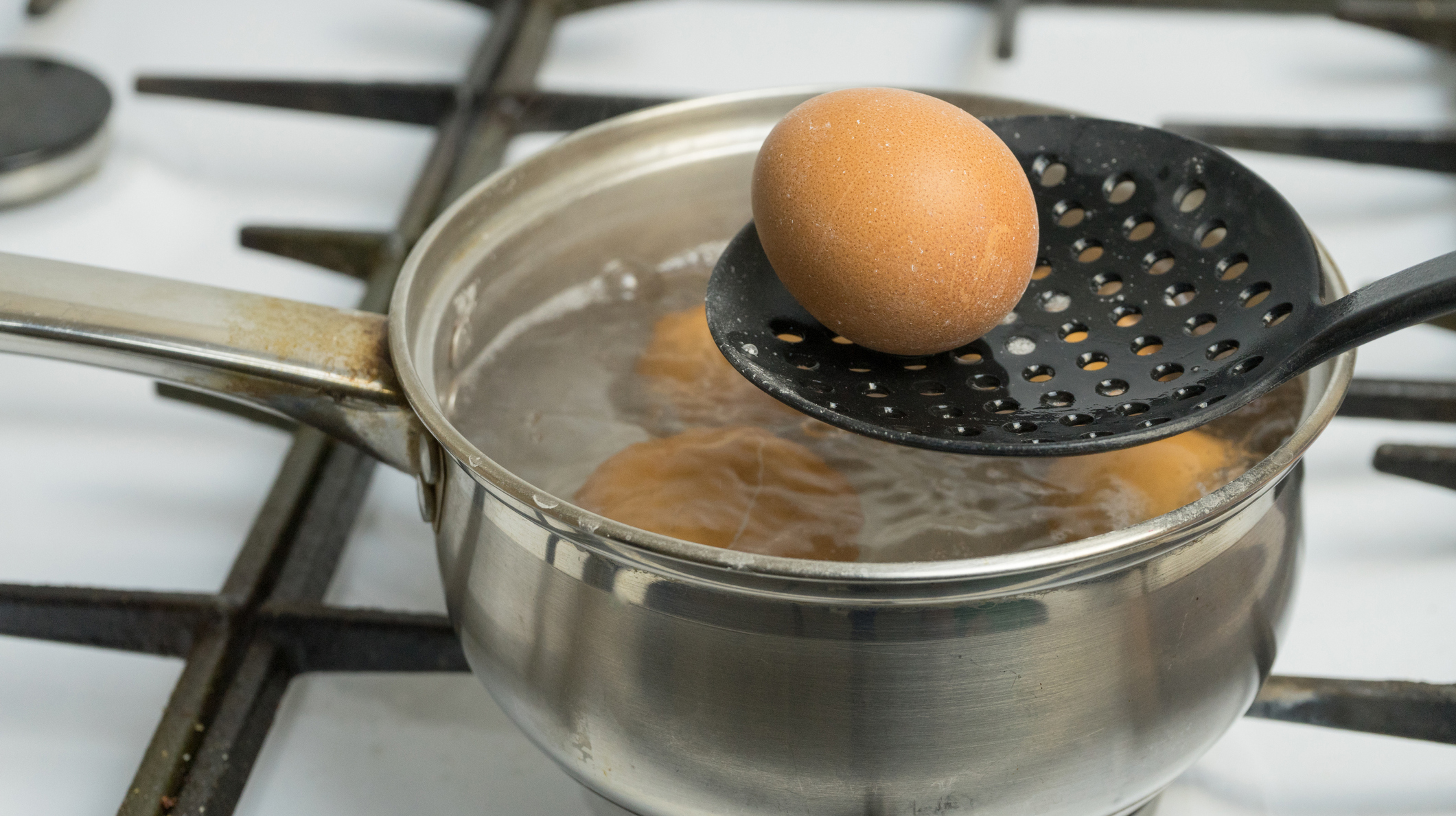 Chicken eggs boil in water. Pan with the product on a gas stove.