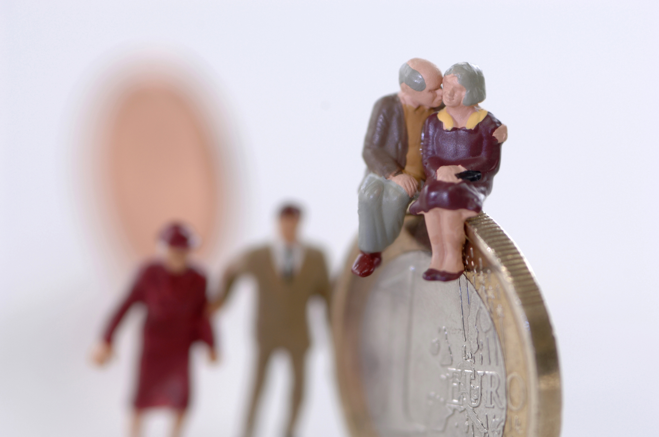 Senior couple sitting on coin, young couple in background, close-up
