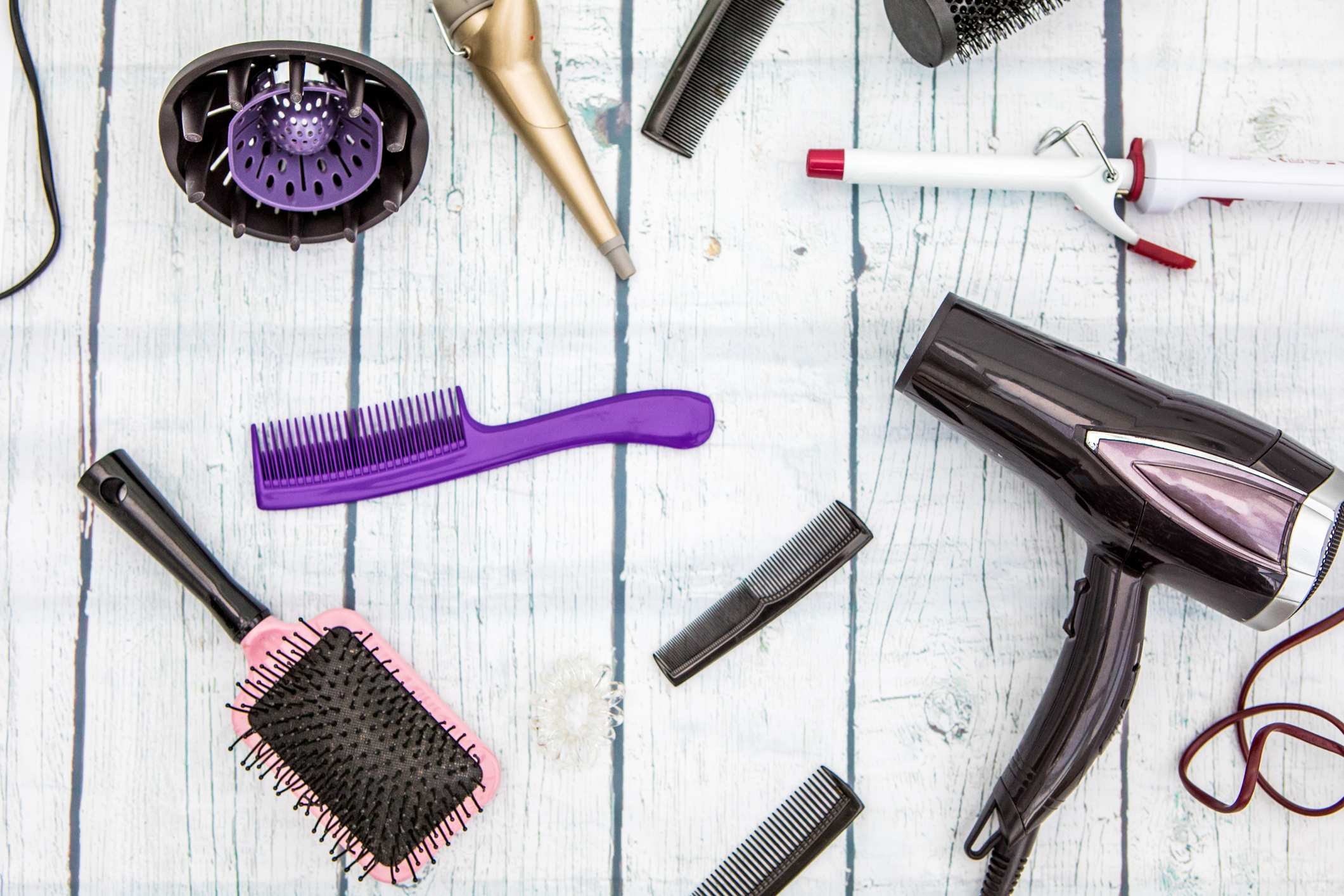 Various hair styling devices on white background, top view