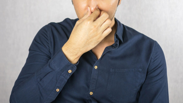 Cover nose gesture by man on grey background