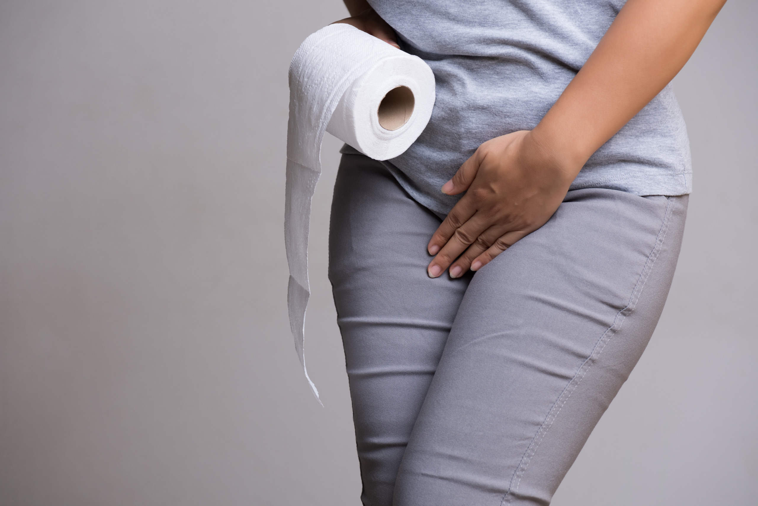 Woman hand holding her crotch lower abdomen and tissue or toilet paper roll. Disorder, Diarrhea, incontinence. Healthcare concept.