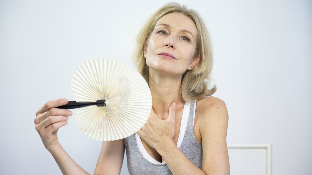 Woman fanning herself to relieve the symptoms of a hot flush.