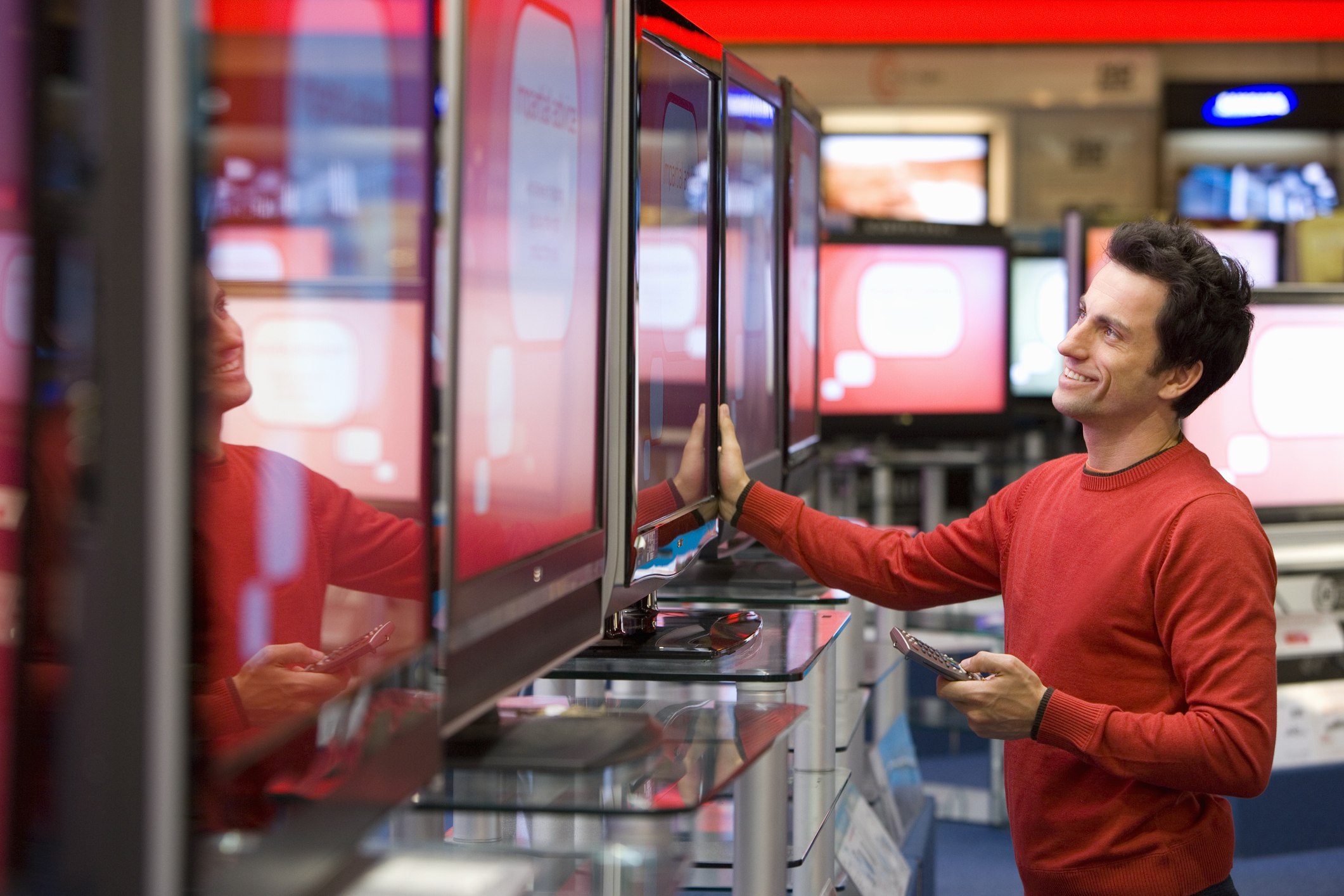 Young man shopping for television, smiling, side view