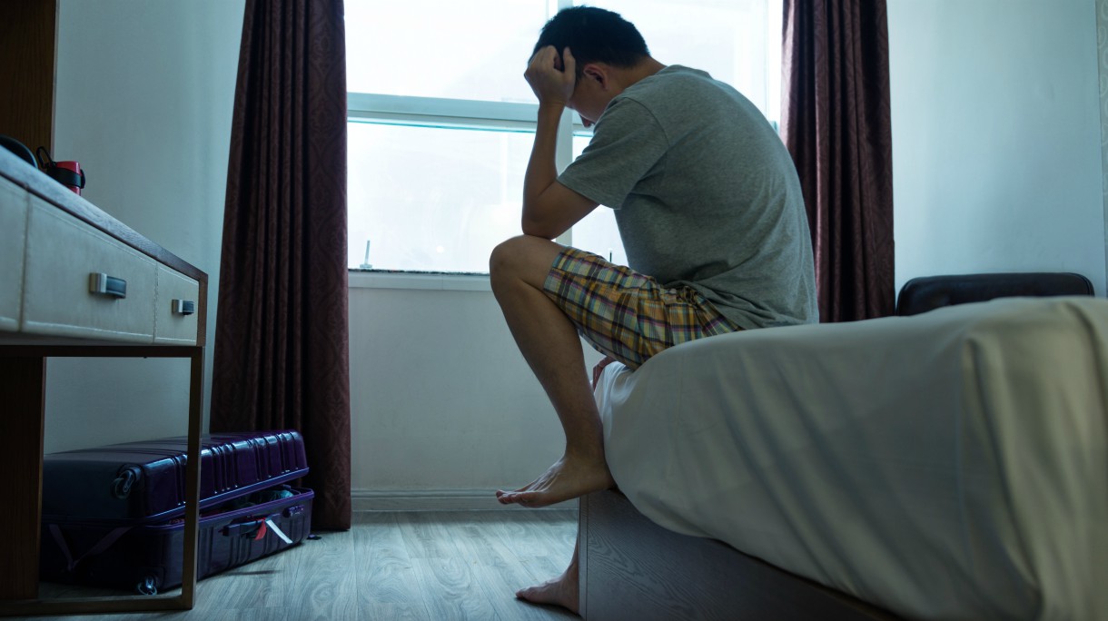 Man sitting on bed with head in hands