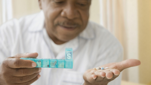 African man holding daily pill box with pills