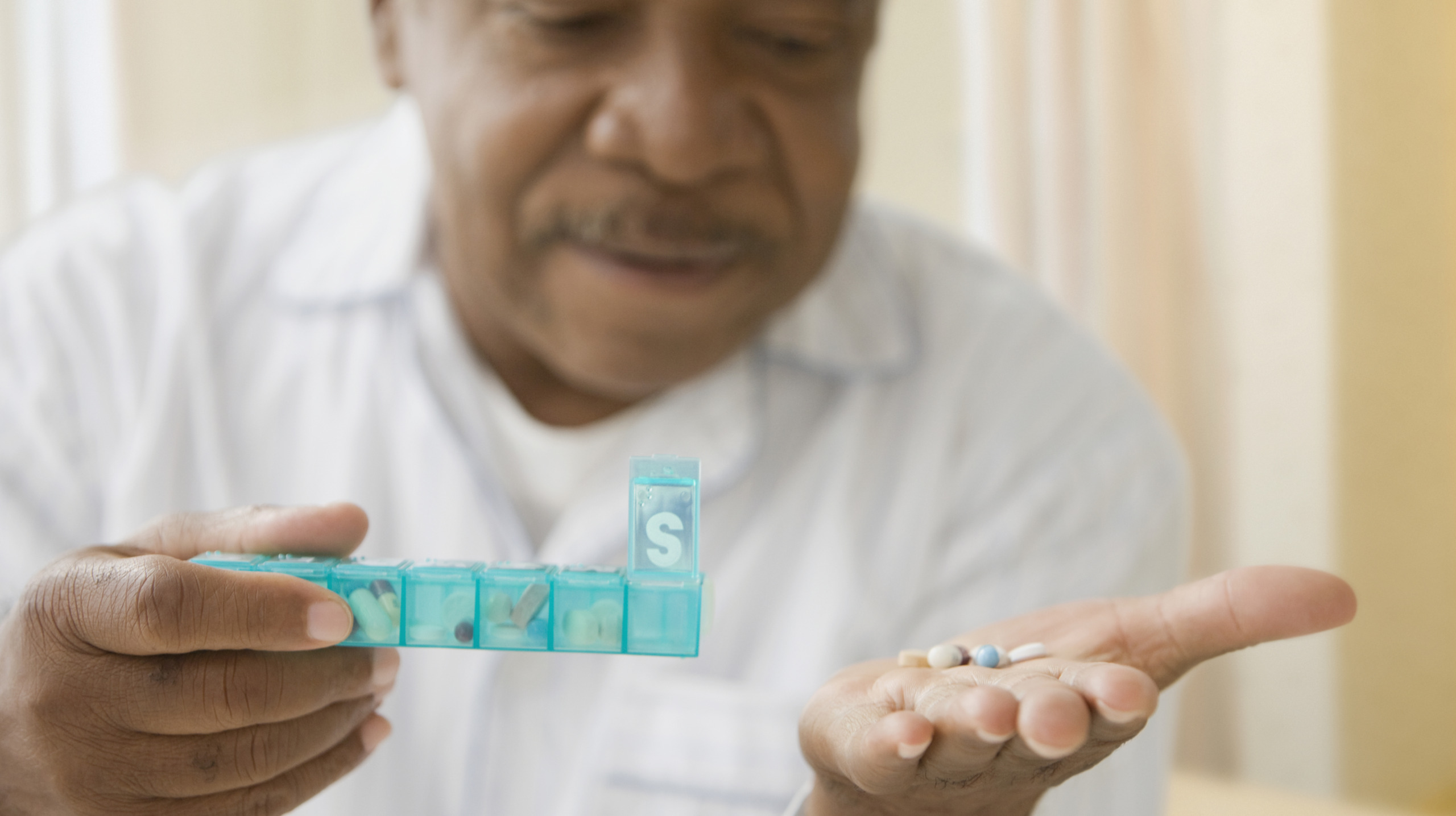 African man holding daily pill box with pills