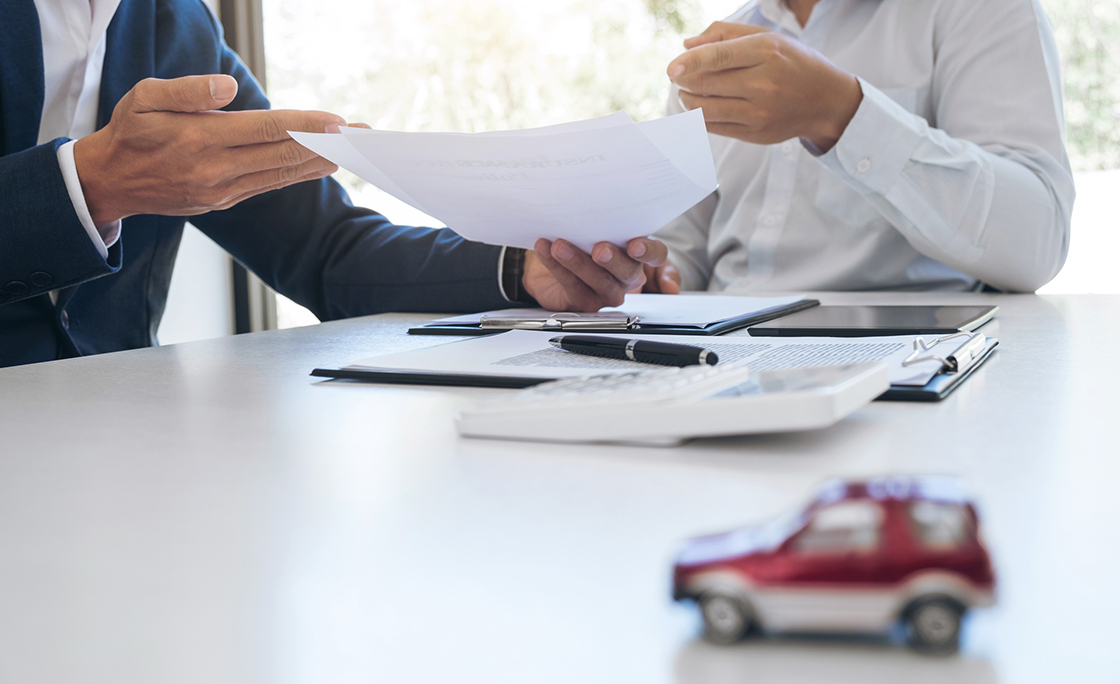 Midsection Of Car Insurance Agent Giving Document To Customer