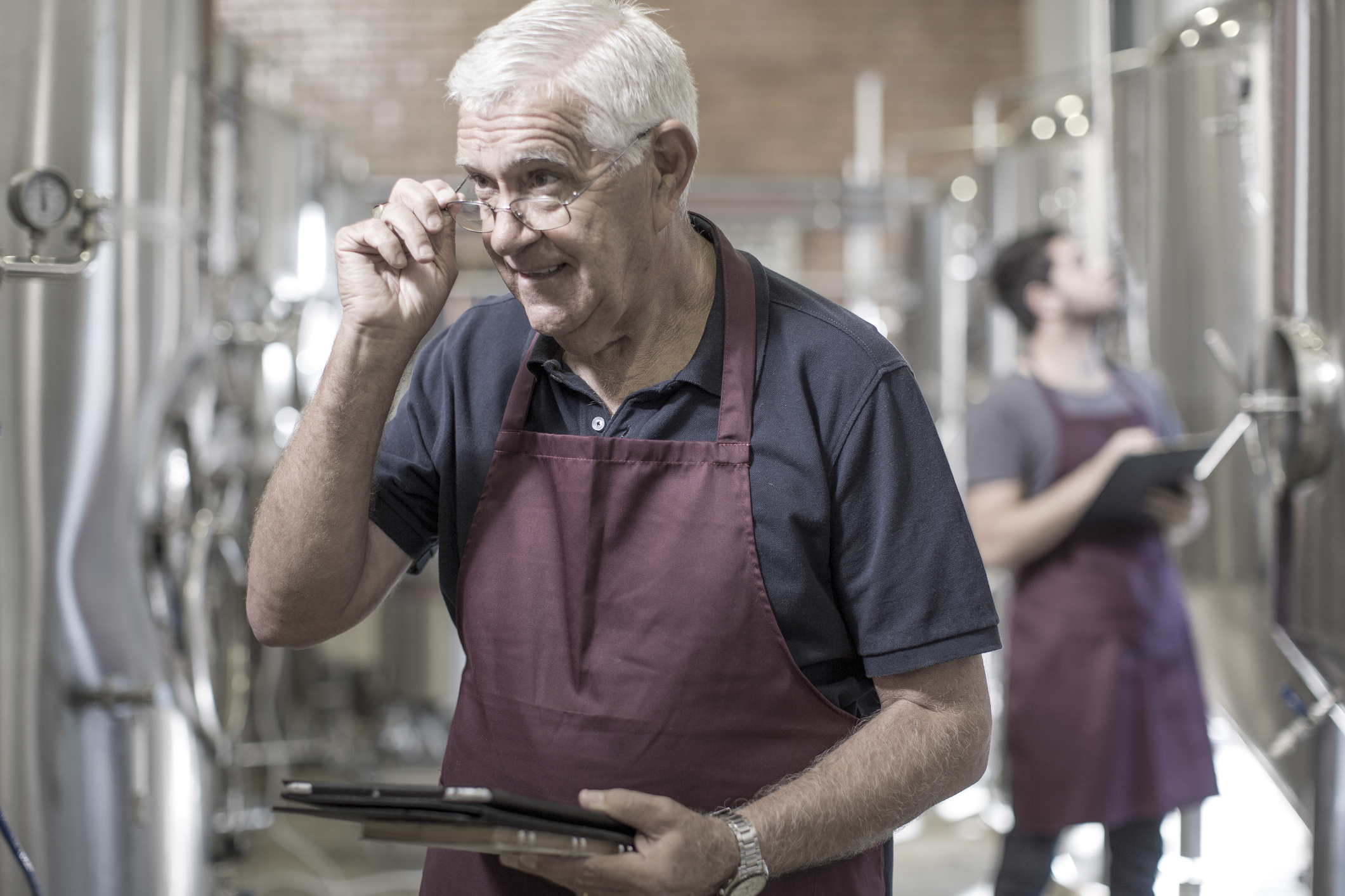 Brewers in brewery standing next to stainless steel tanks