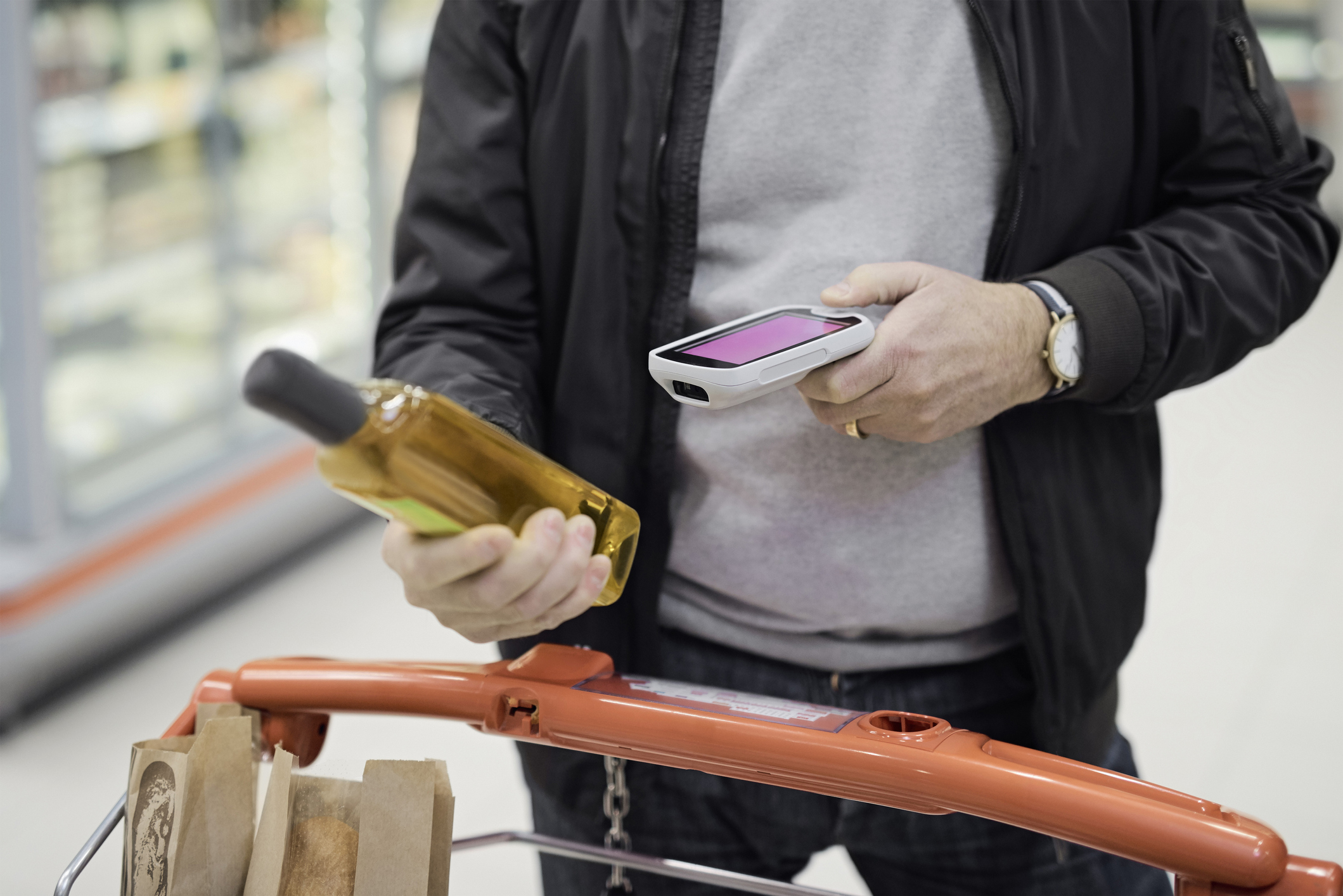 Midsection of man scanning olive oil bottle at supermarket