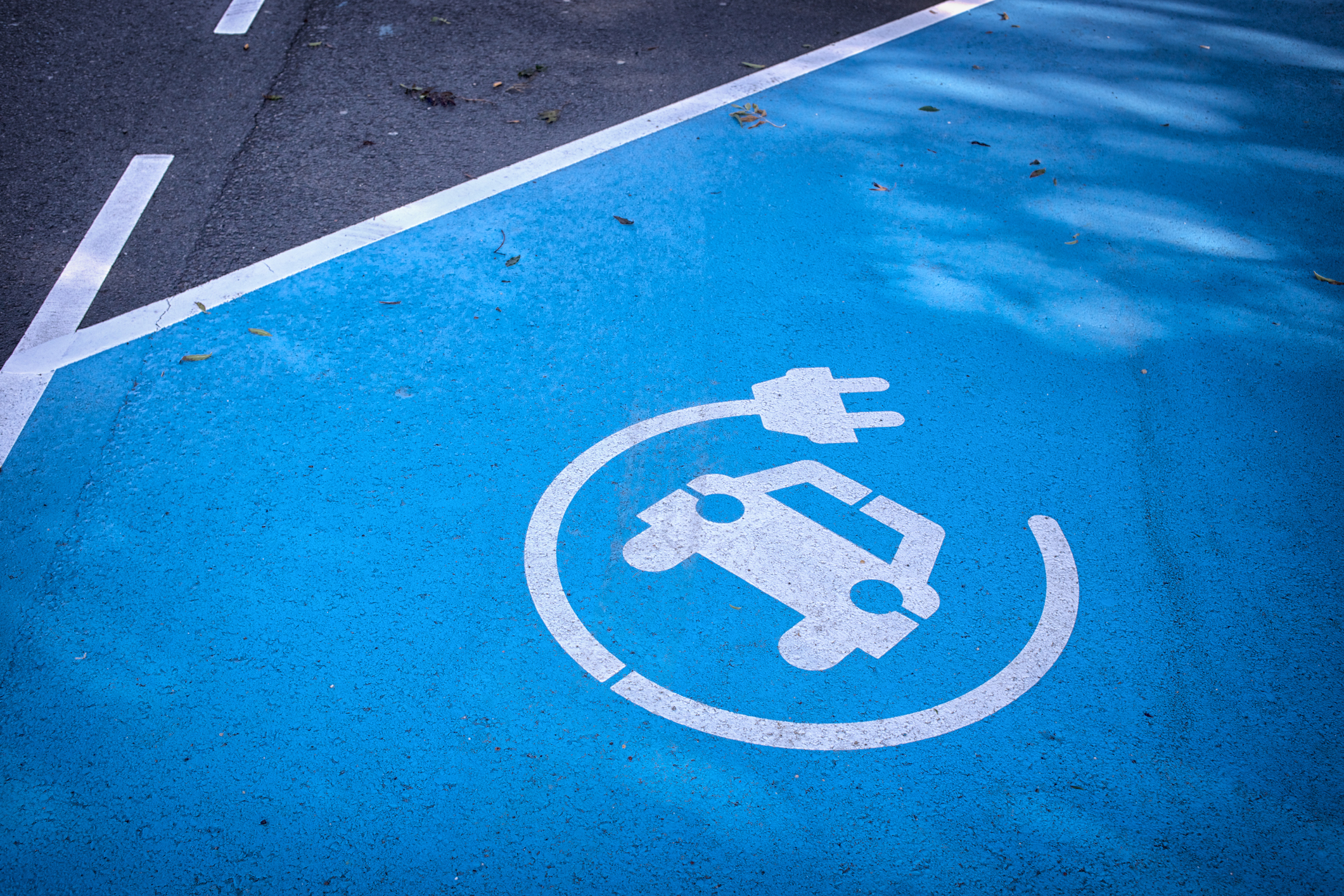 Logo ‘charge your car here’ on blue parking lot