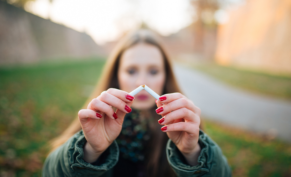 Young Woman Breaking Cigarette On Field
