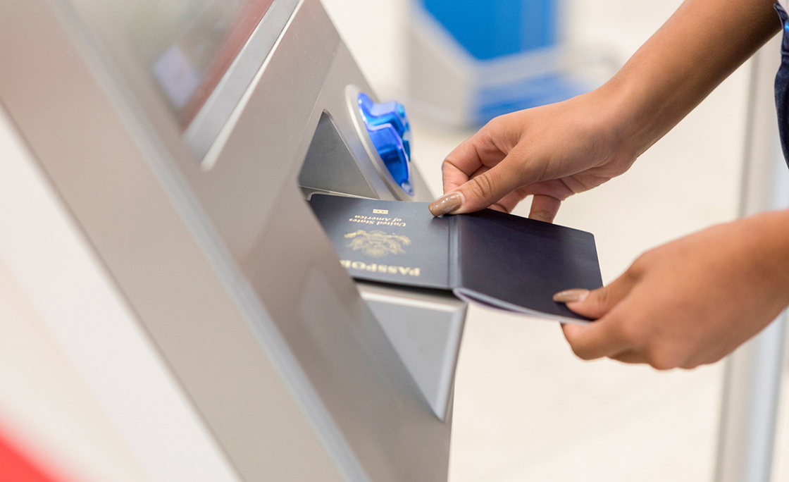Unrecognizable woman scans passport at airport kiosk