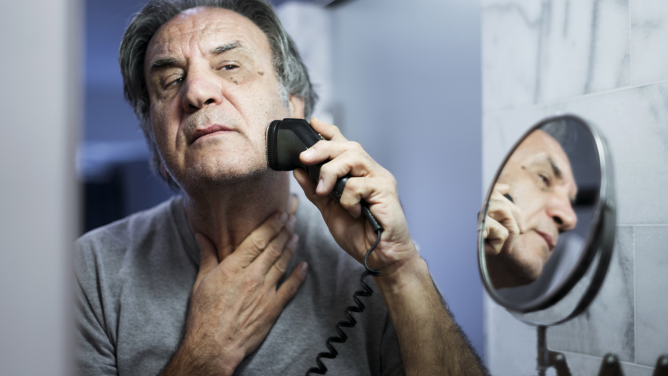 Senior man shaving his beard in bathroom