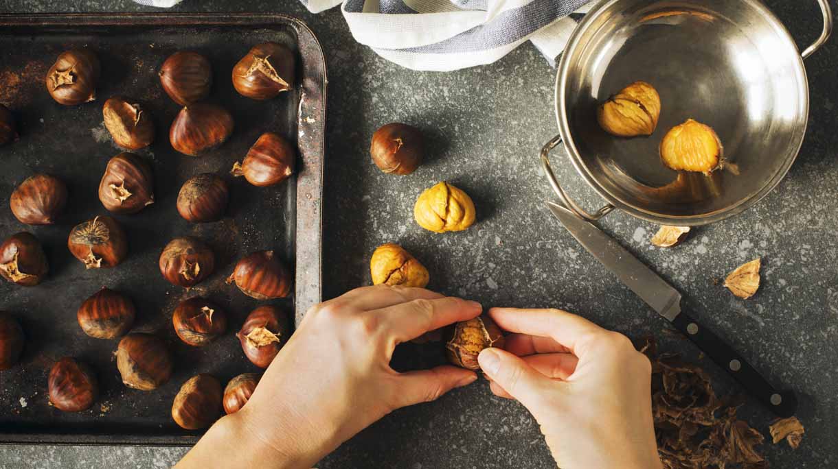 Roasted chestnuts. Woman’s hands peeling a chestnuts