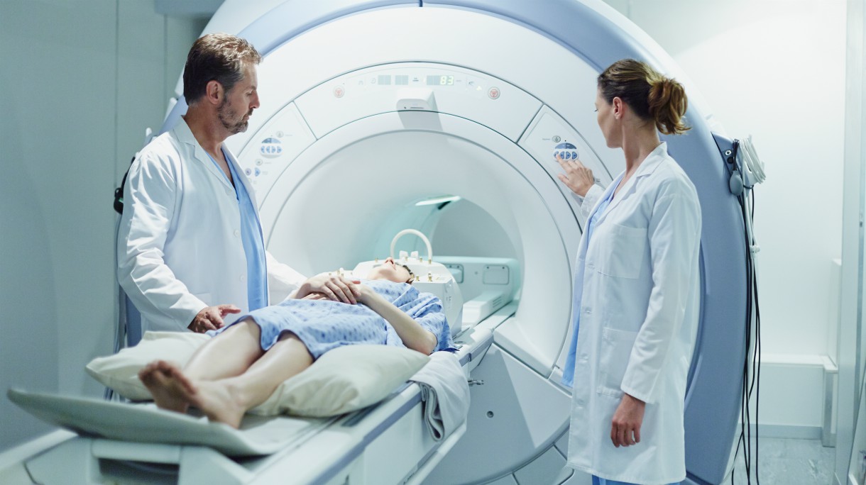 Male and female doctors preparing patient for CAT scan in hospital