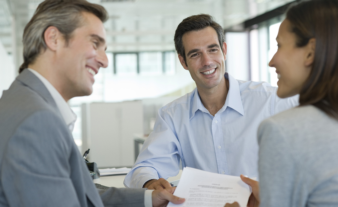 Smiling couple discussing contract with adviser