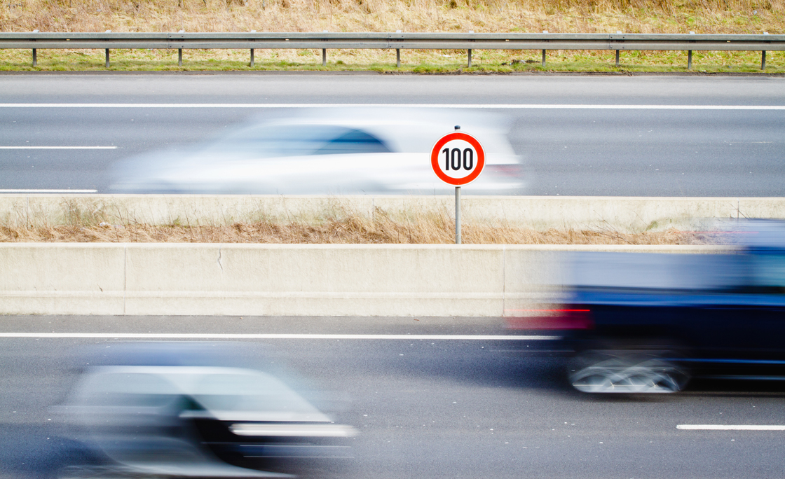 Speed Limit Sign Amidst Blur Cars On Street