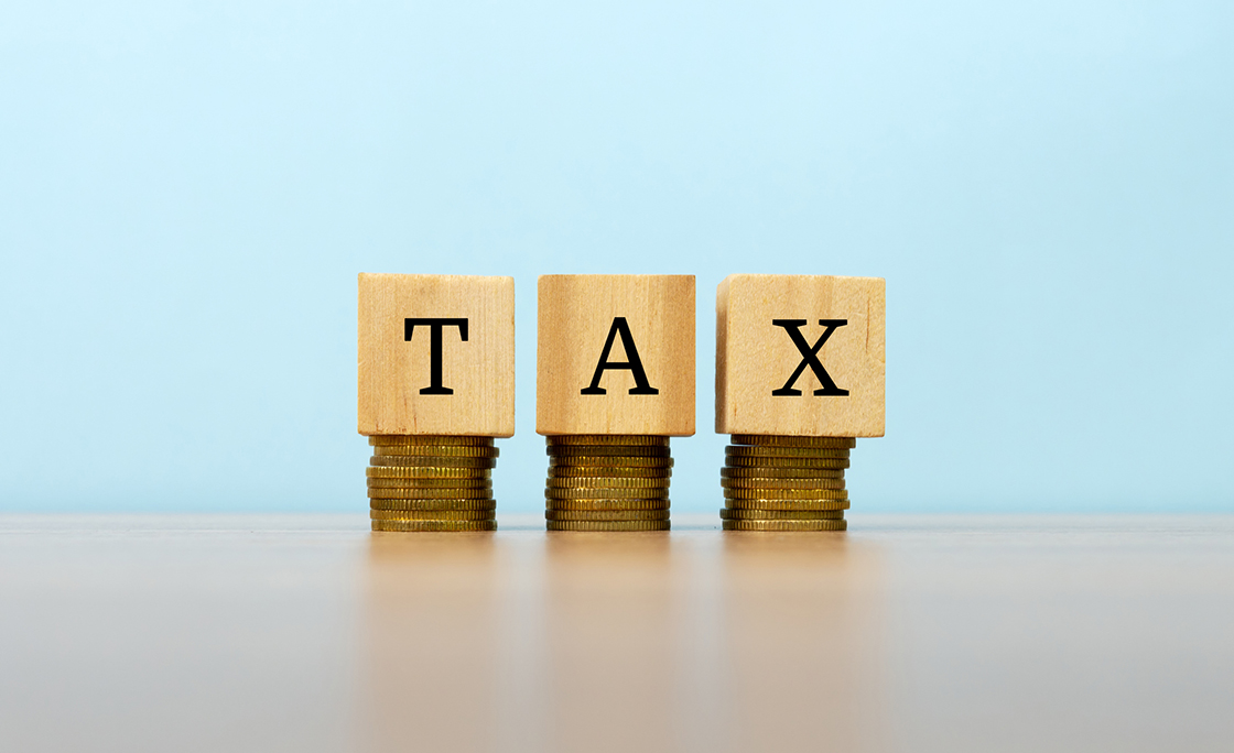 Tax text written on wooden block with stacked coins