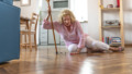 Helpless retired woman with blonde hair sitting on floor at home.The risks that come with getting older.