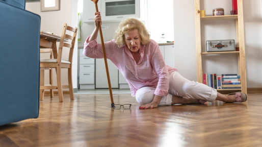 Helpless retired woman with blonde hair sitting on floor at home.The risks that come with getting older.