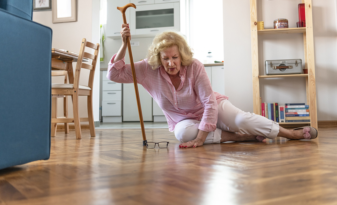 Helpless retired woman with blonde hair sitting on floor at home.The risks that come with getting older.