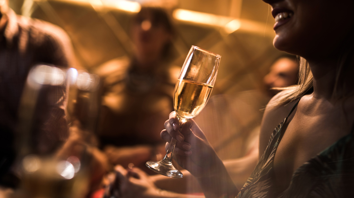 Close up of woman holding glass of Champagne in nightclub.