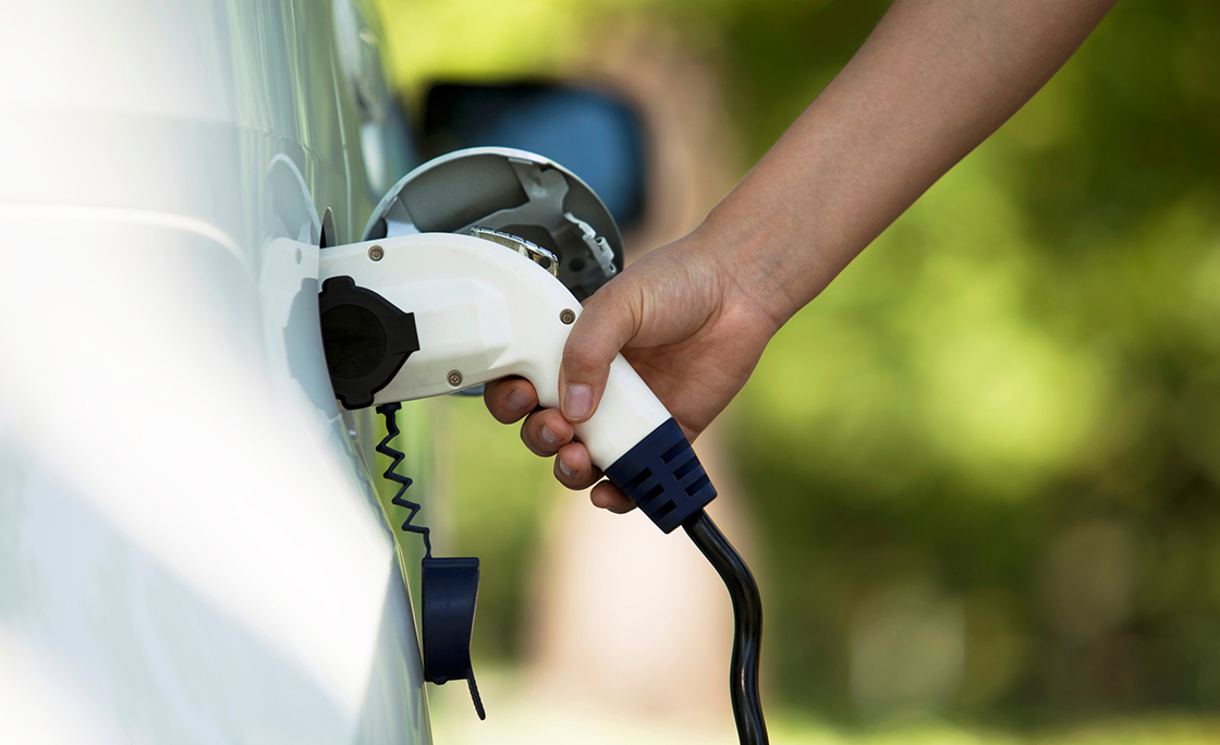 Cropped Hand Charging Car At Station
