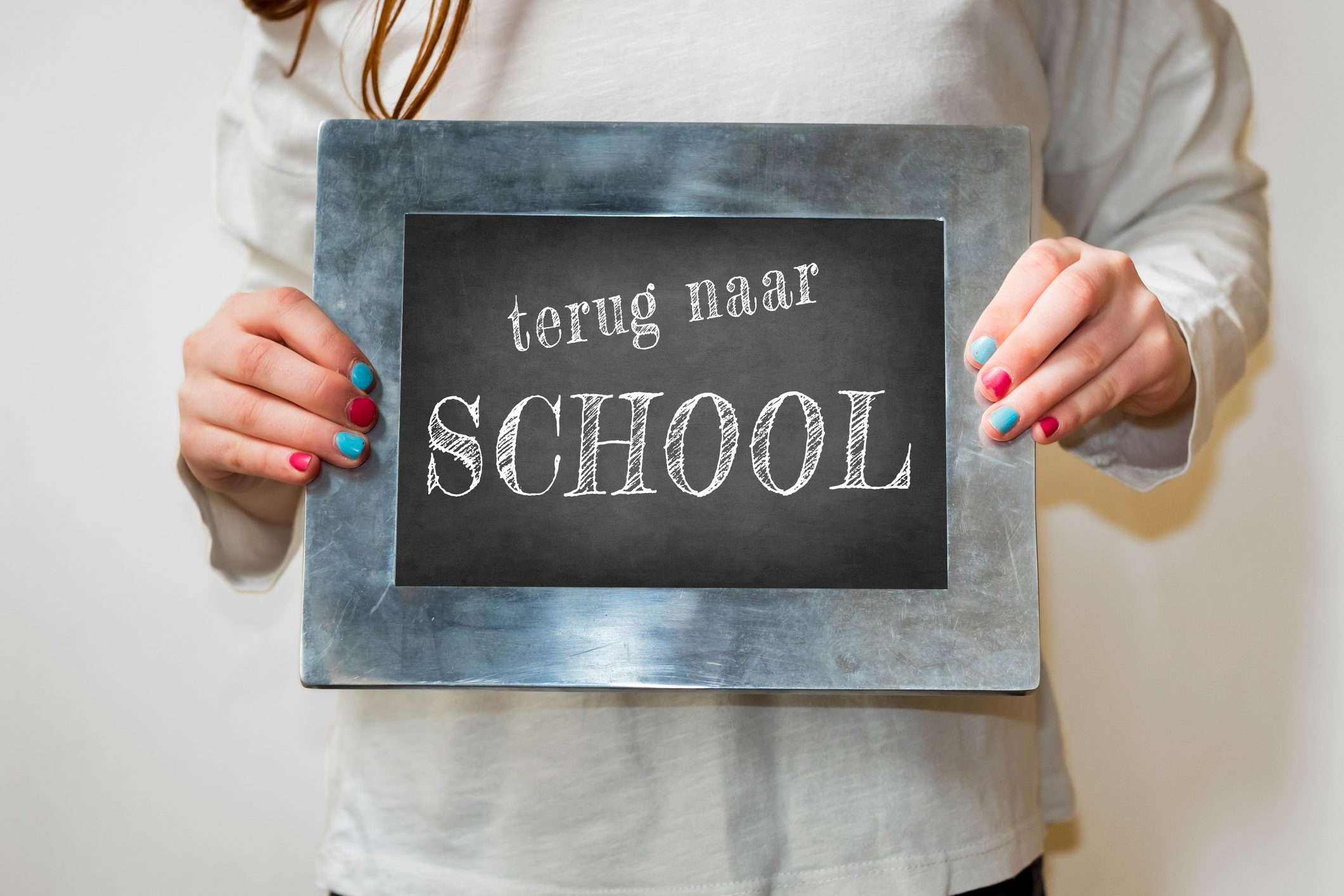 Child holding up a blackboard with the Dutch words for Back to School