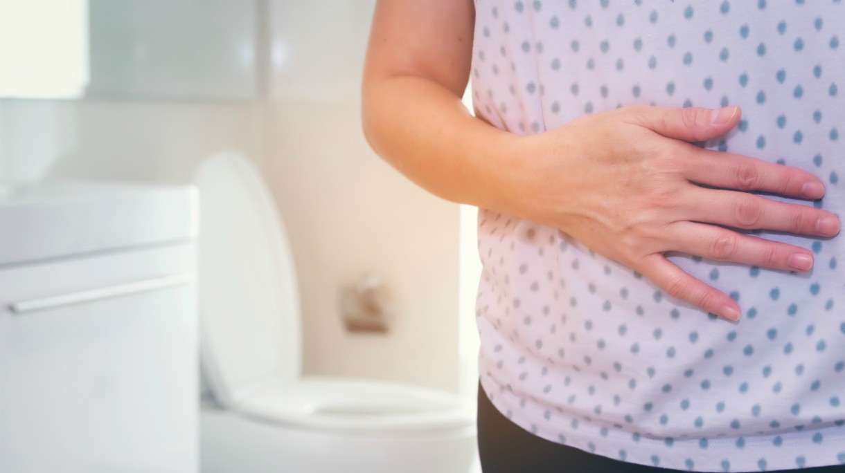 One woman is having a stomachache in front of the toilet.