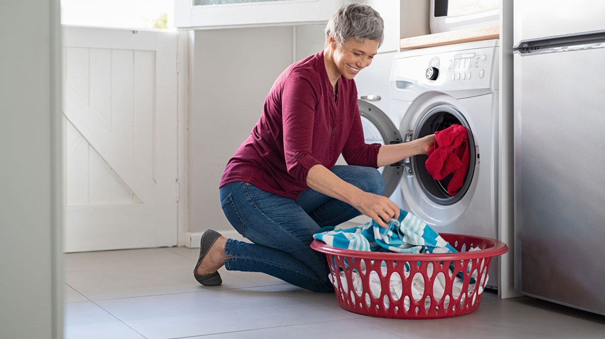 Vrouw doet kleding in de wasmachine