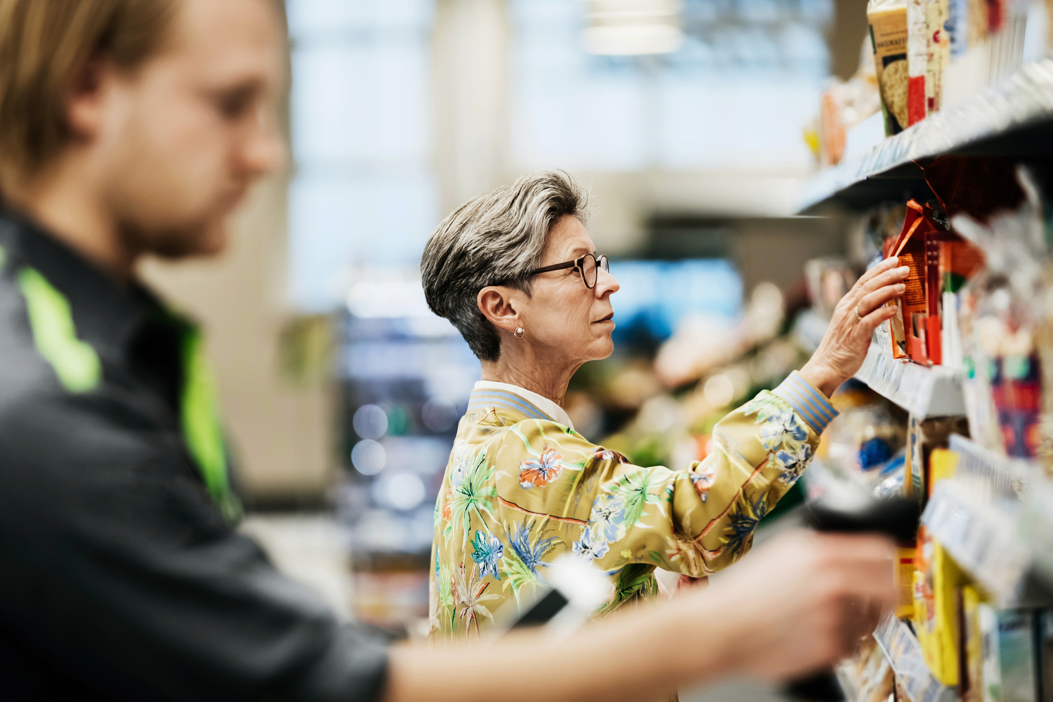 Senior Woman Picking Goods From Shelf At Supermarket