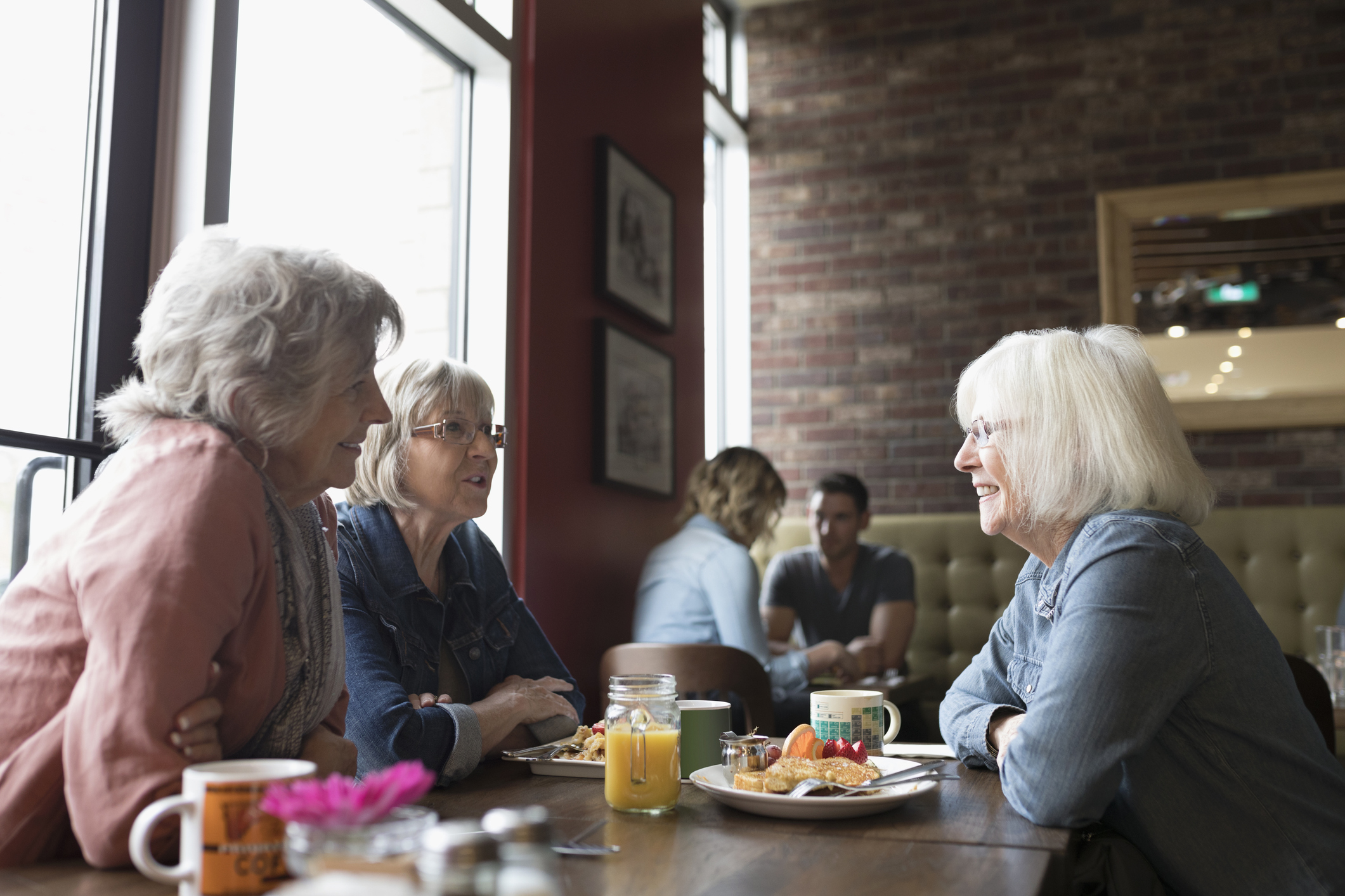 Senior women talking, eating brunch at diner table
