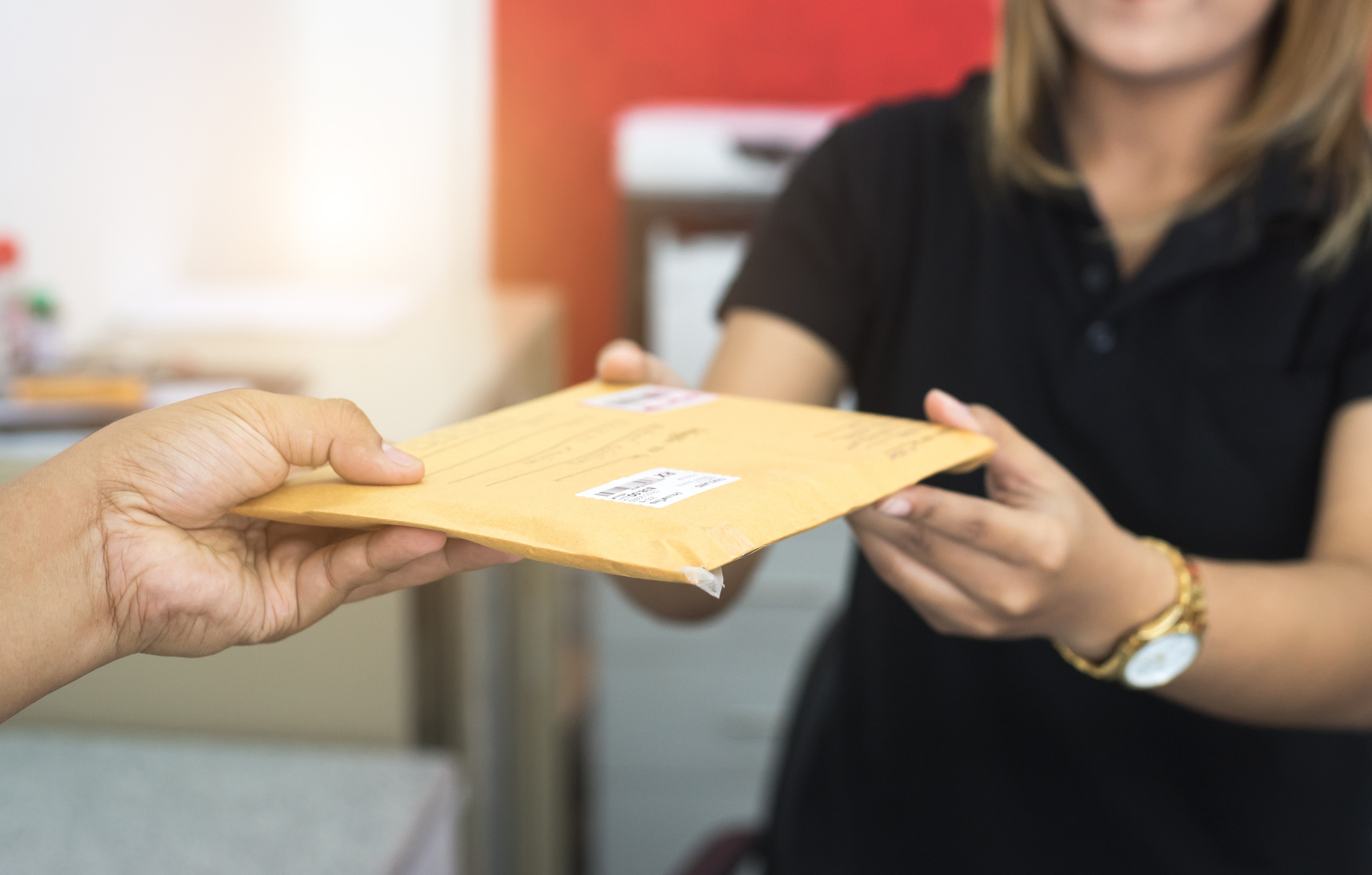 male hand send mail envelope to the female of post office before sending