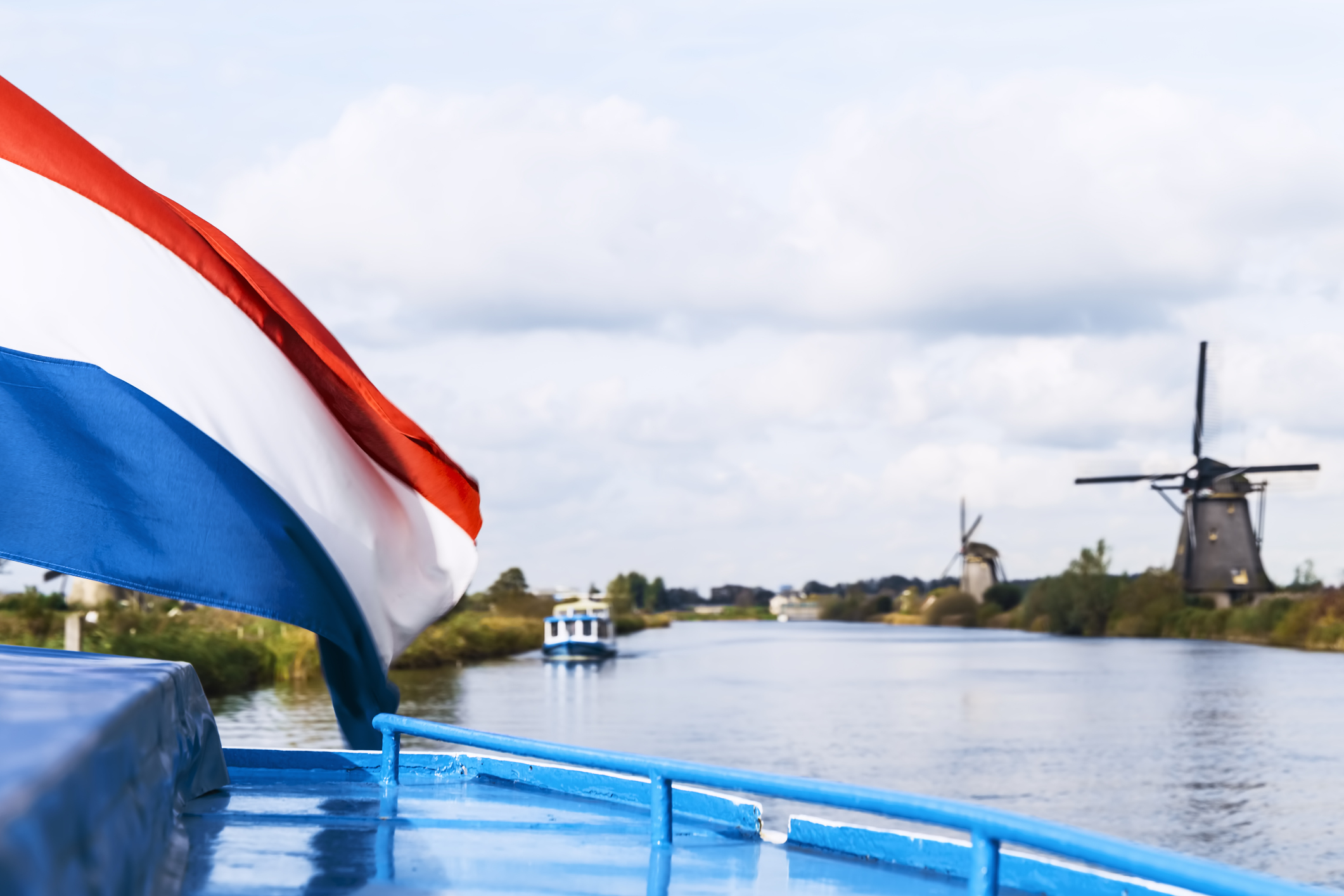 Dutch Flag Waving In The Wind Against Windmills, Kinderdijk, Netherlands