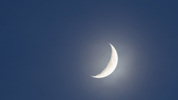 Crescent moon against clear sky at night.