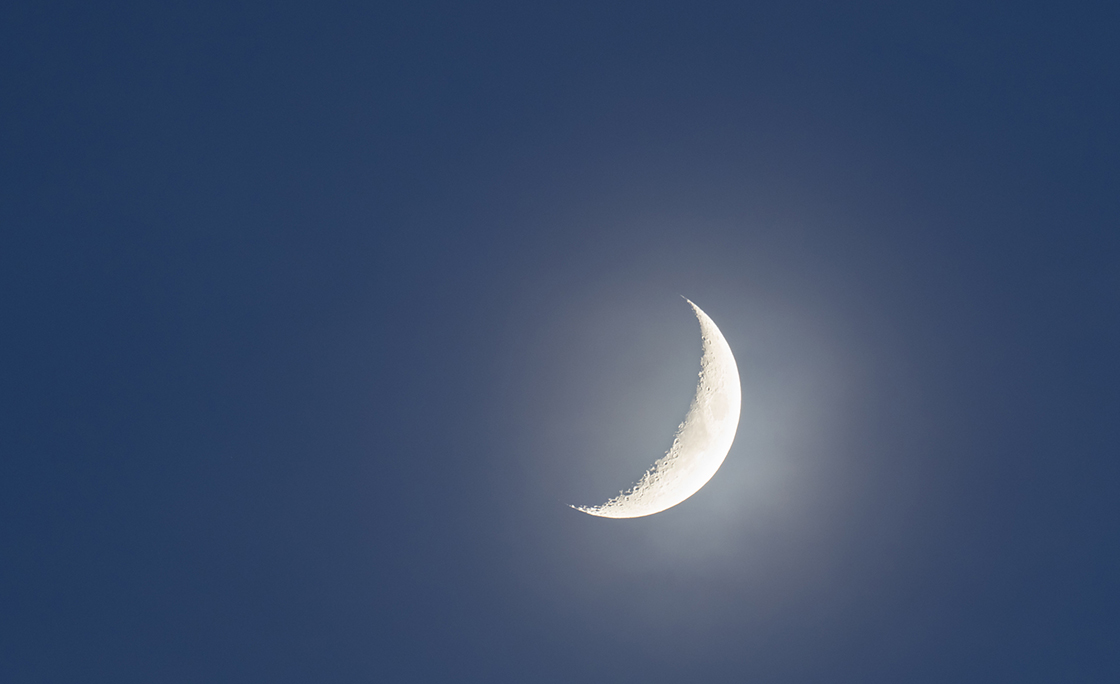 Crescent moon against clear sky at night.