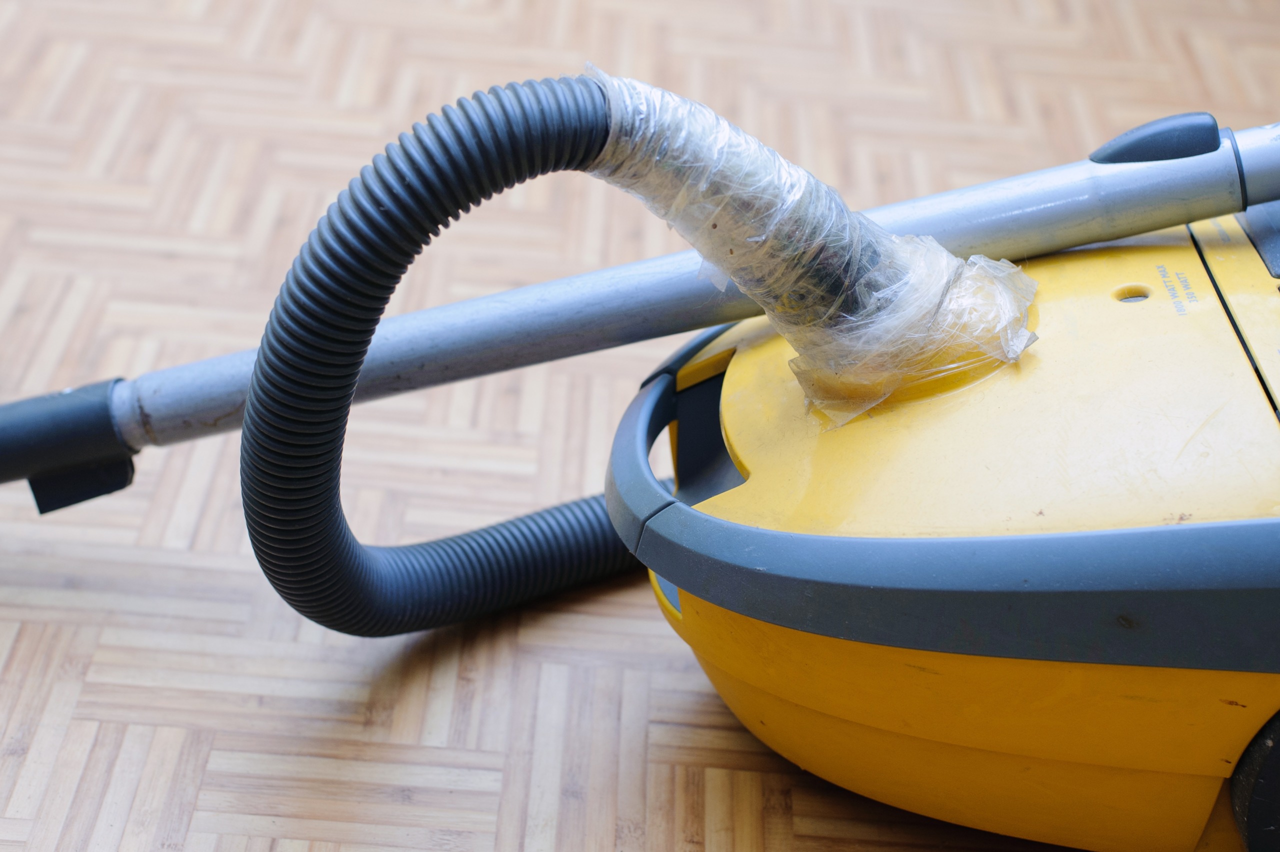 a broken vacuum cleaner. Torn Hose wrapped in duct tape