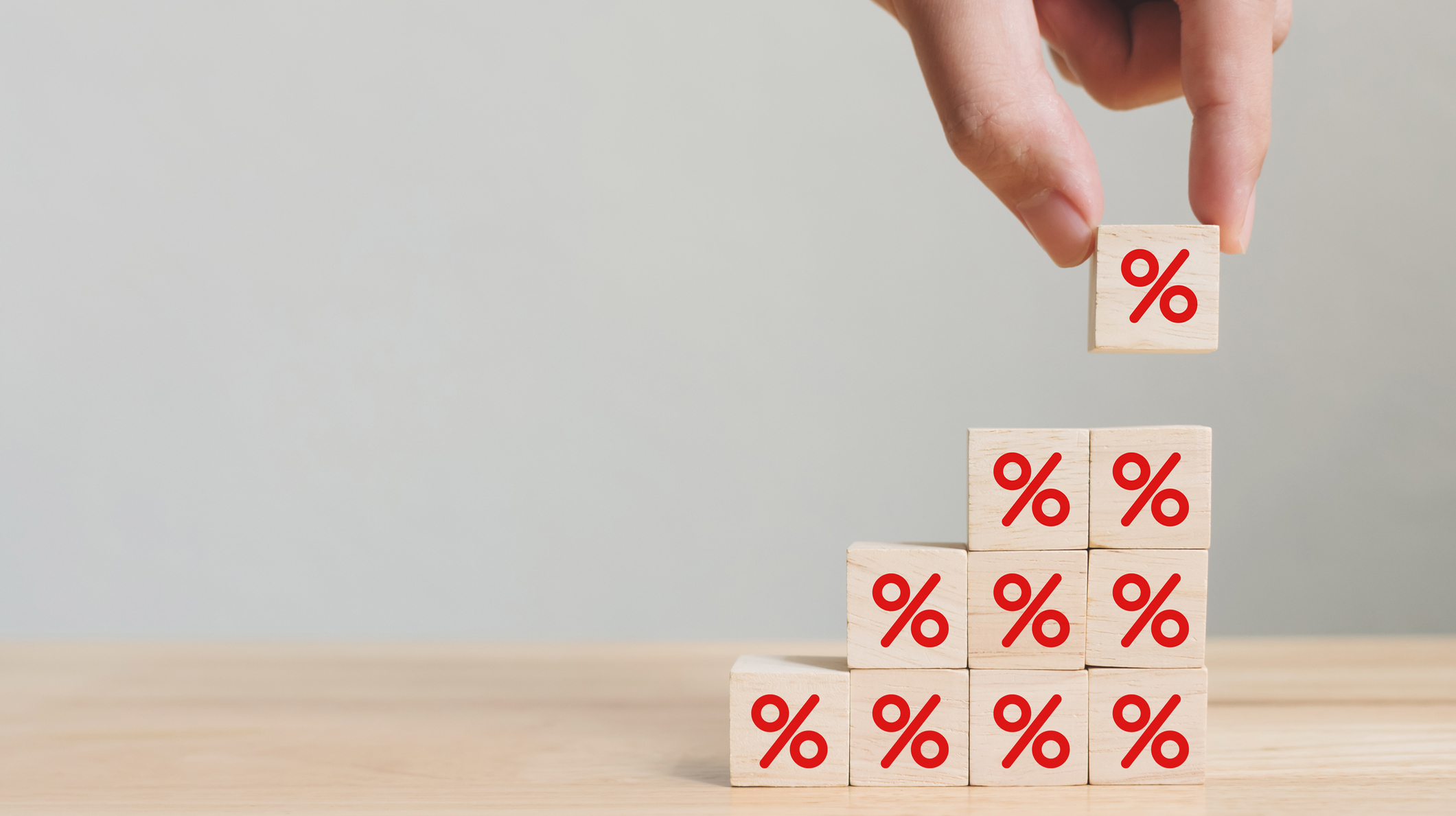 Interest rate financial and mortgage rates concept. Hand putting wood cube block increasing on top with icon percentage symbol upward direction