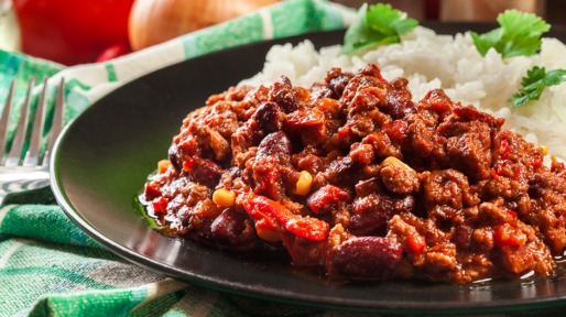 Hot chili con carne with ground beef, beans, tomatoes and corn served with rice