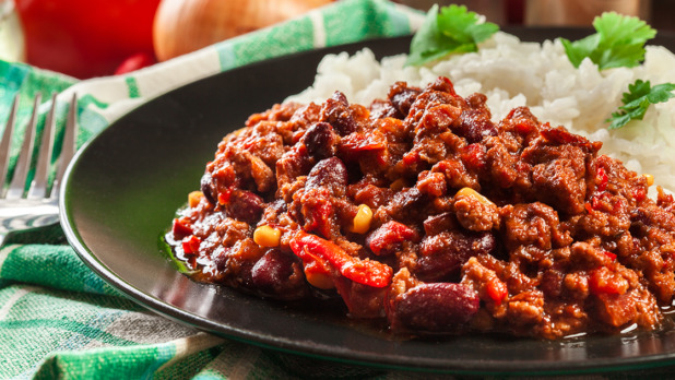 Hot chili con carne with ground beef, beans, tomatoes and corn served with rice