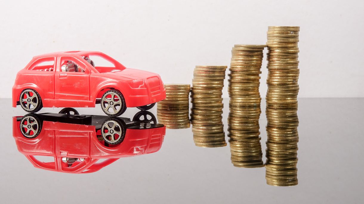 Close-Up Of Toy Cars And Coins On Table Against White Background