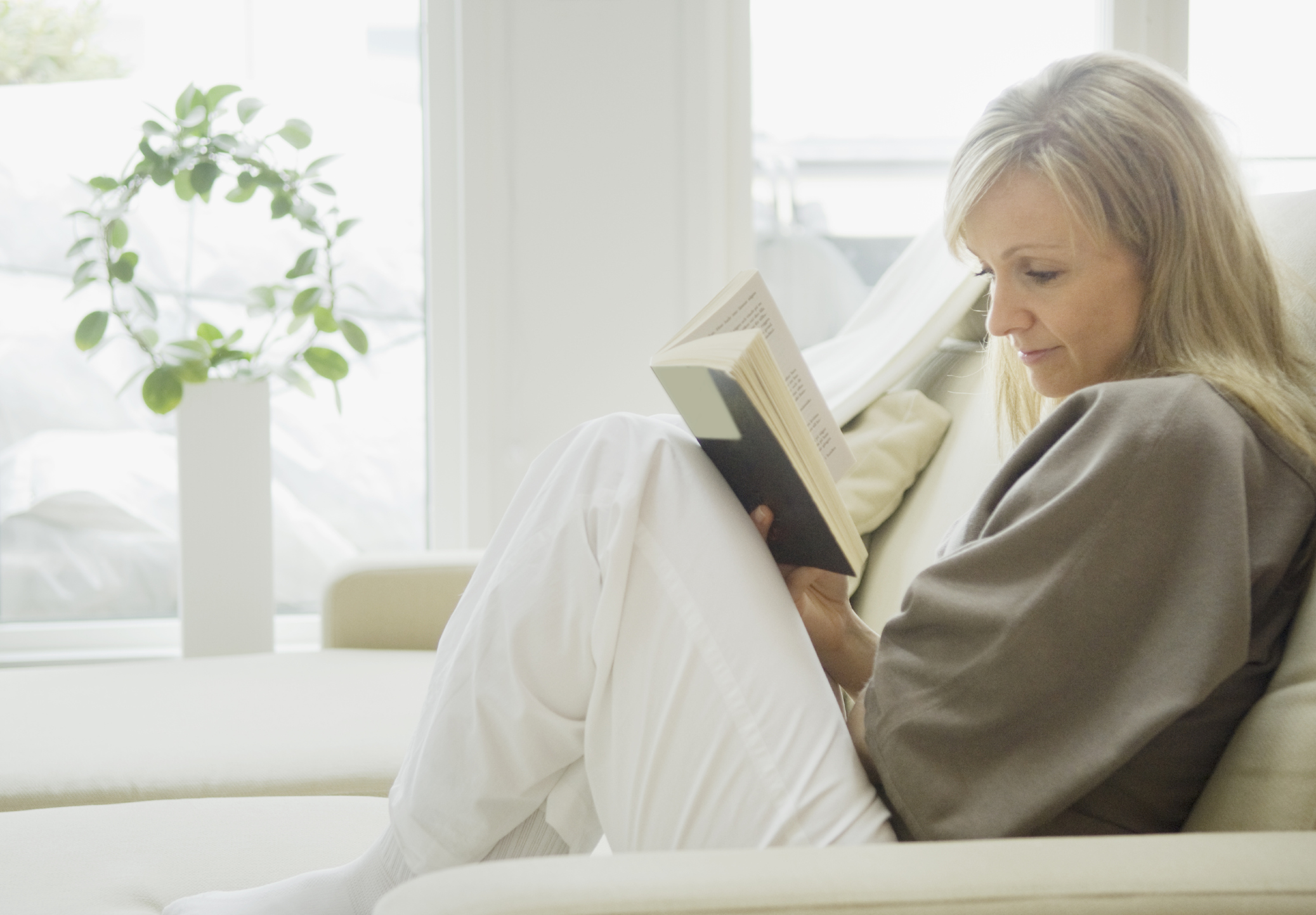 Woman reading book on sofa