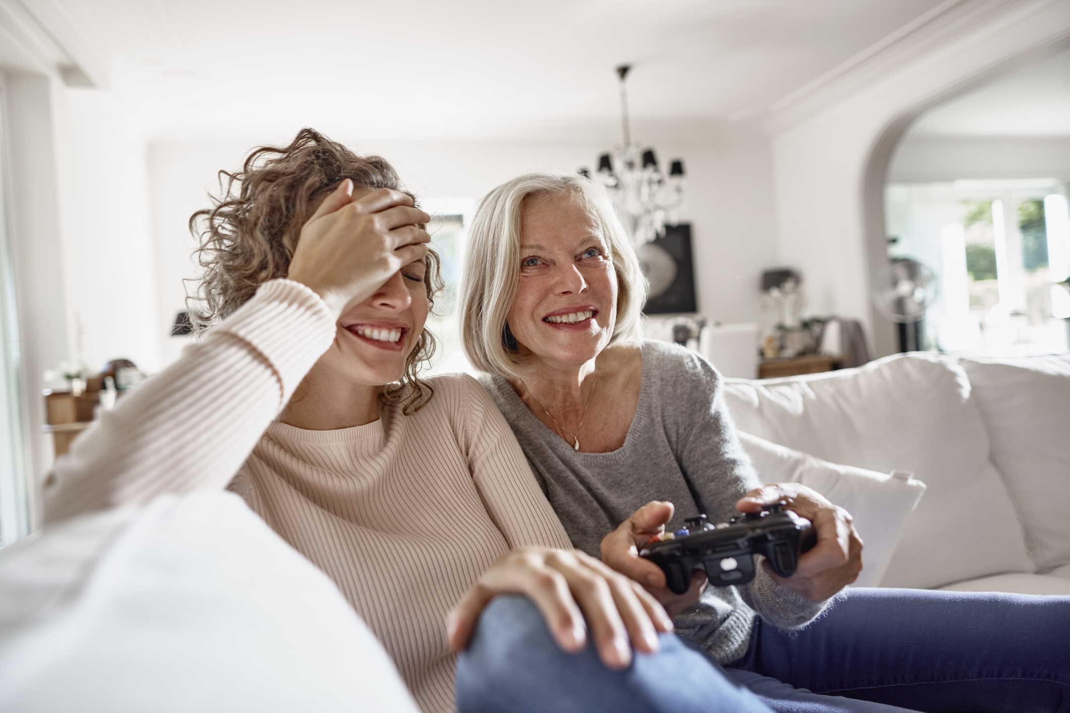 Happy mother and adult daughter playing video game at home