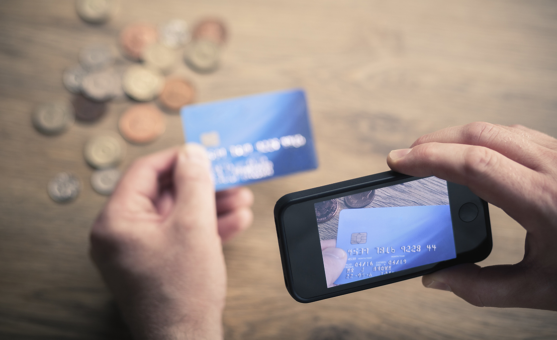Mans hands photographing credit card using smartphone