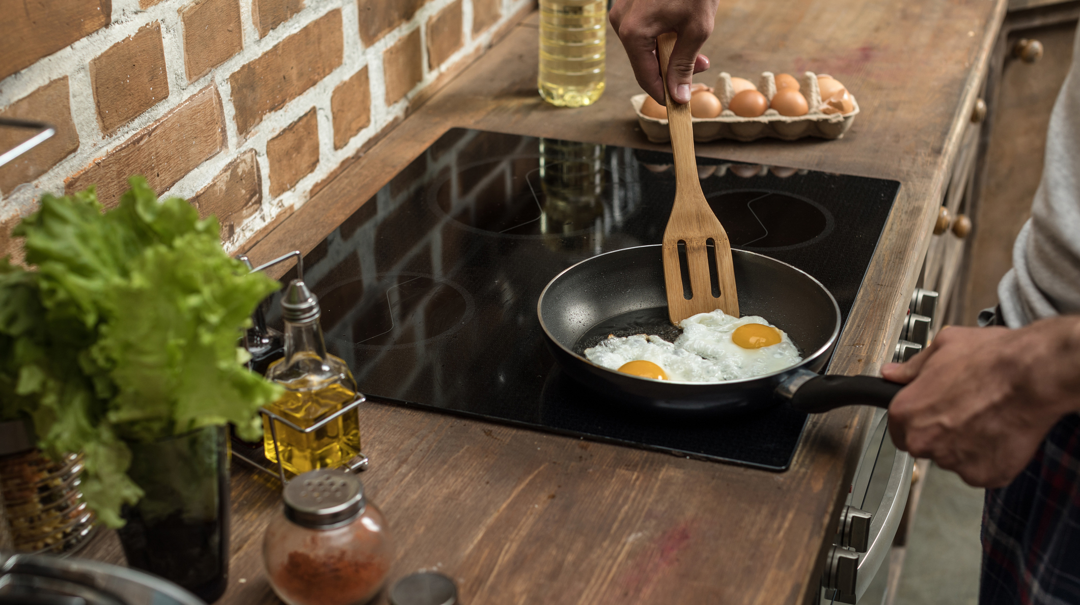 partial view of young man preparing eggs for breakfast in kitchen at home