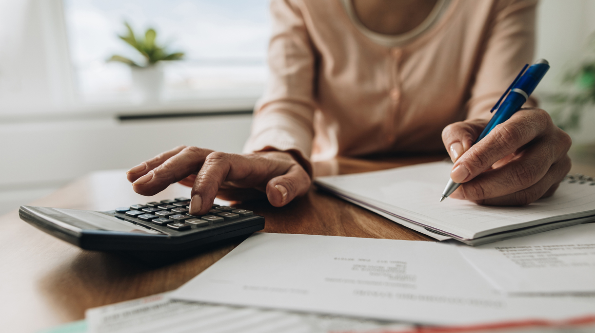 Close up of woman planning home budget and using calculator.